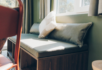 Sunny bench seating with plush cushions by the window in Koya Tiny Loft, Wilsumer Berge, Germany.
