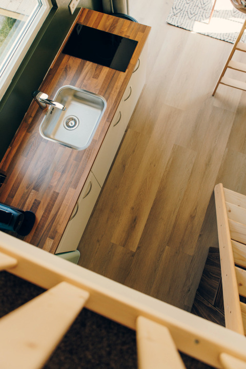 Top-down view of a compact kitchen with wooden countertop in Koya Tiny Loft at Wilsumer Berge, Germany.
