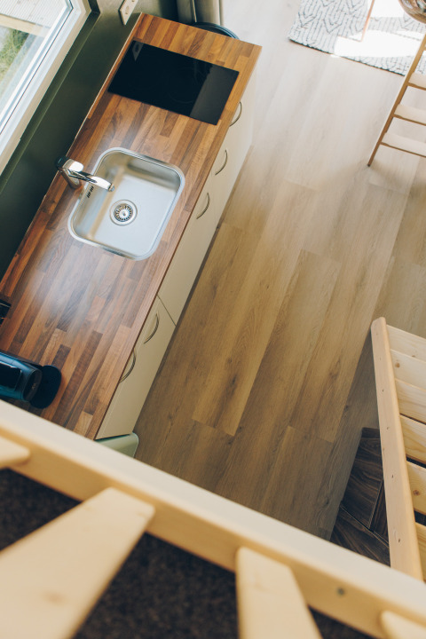 Top-down view of a compact kitchen with wooden countertop in Koya Tiny Loft at Wilsumer Berge, Germany.