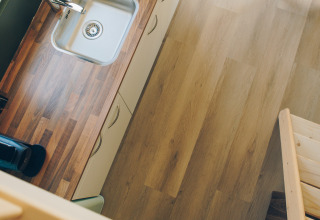 Top-down view of a compact kitchen with wooden countertop in Koya Tiny Loft at Wilsumer Berge, Germany.