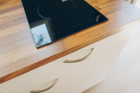 A modern induction cooktop installed in a wooden countertop at Koya Tiny Loft, Wilsumer Berge, Germany.