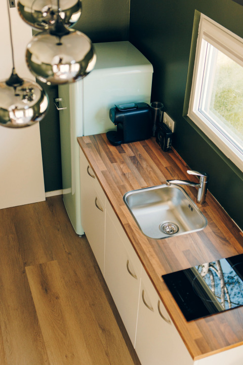 Modern tiny kitchen in Koya Tiny Loft featuring wood countertop, sink, fridge, and coffee maker, Wilsumer Berge.