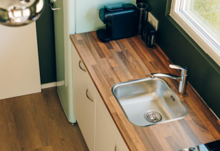 Modern tiny kitchen in Koya Tiny Loft featuring wood countertop, sink, fridge, and coffee maker, Wilsumer Berge.