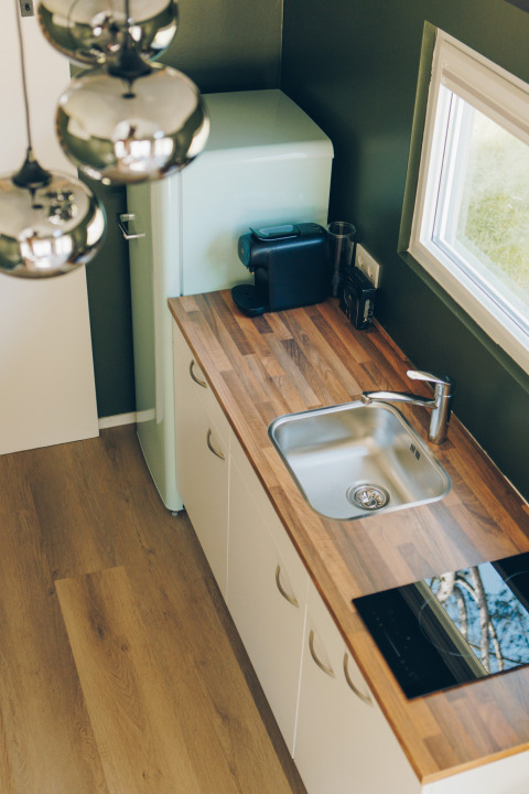 Modern tiny kitchen in Koya Tiny Loft featuring wood countertop, sink, fridge, and coffee maker, Wilsumer Berge.