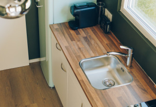 Modern tiny kitchen in Koya Tiny Loft featuring wood countertop, sink, fridge, and coffee maker, Wilsumer Berge.