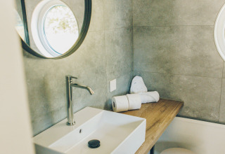 Modern bathroom at Koya Tiny Loft, Wilsumer Berge, Germany, featuring a sink, mirror, and wood counter.