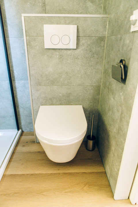 Modern wall-mounted toilet with wood flooring in the bathroom of Koya Tiny Loft, Wilsumer Berge, Germany.