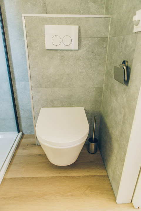 Modern wall-mounted toilet with wood flooring in the bathroom of Koya Tiny Loft, Wilsumer Berge, Germany.