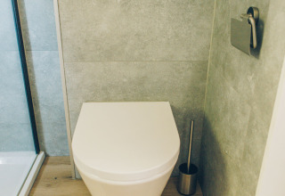 Modern wall-mounted toilet with wood flooring in the bathroom of Koya Tiny Loft, Wilsumer Berge, Germany.