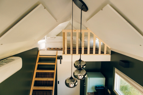 Interior of Koya Tiny Loft at Wilsumer Berge, Germany, featuring a loft bed, wooden ladder, and pendant lights.