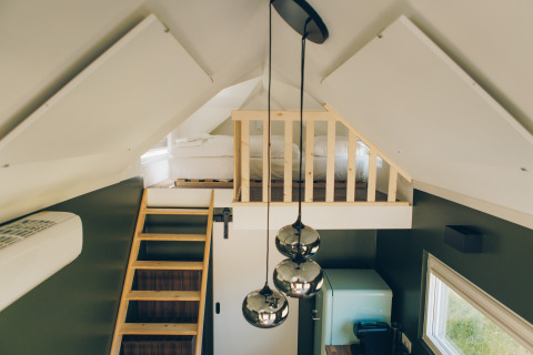 Interior of Koya Tiny Loft at Wilsumer Berge, Germany, featuring a loft bed, wooden ladder, and pendant lights.