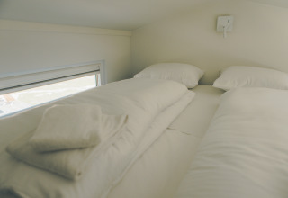 Cozy sleeping area with two beds and white linens in Koya Tiny Loft, Wilsumer Berge, Germany.