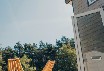 Terrasse ensoleillée avec deux chaises en bois à Koya Tiny Loft, Wilsumer Berge, Allemagne, entourée de nature.