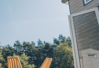 Sunny deck with two wooden chairs at Koya Tiny Loft, Wilsumer Berge, Germany, surrounded by nature.