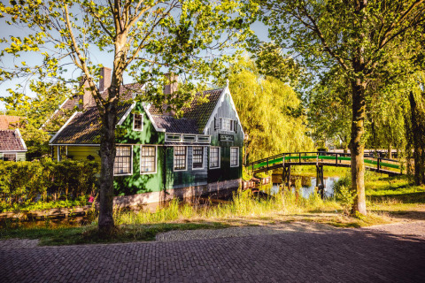 Cabañas verdes encantadoras y puente de madera en un parque vacacional de glamping junto a un canal.