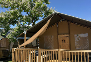 Tenda safari 'Outback' al Camping Terme Tuhelj in Croazia, veranda in legno e albero fiorito in giornata soleggiata.