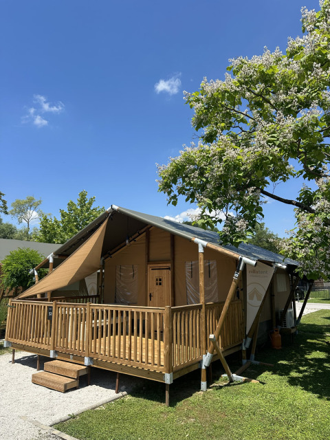 Tenda safari 'Outback' al Camping Terme Tuhelj in Croazia, immersa nel verde e sotto un cielo limpido.