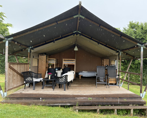 Safari-Zelt auf Camping de Regenboog in Tschechien mit überdachter Terrasse, Sitzplätzen und Betten.