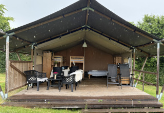 Safari-Zelt auf Camping de Regenboog in Tschechien mit überdachter Terrasse, Sitzplätzen und Betten.