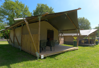 Safari-Zelt auf dem Campingplatz De Rammelbeek in den Niederlanden, mit Terrasse und Gartenmöbeln.