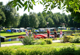 Families walking near colorful kayaks and tents at Hunzepark holiday park in Drenthe, Netherlands.