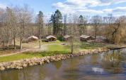 Tentes safari au bord d’un étang à Hunzepark, Pays-Bas, entourées d’arbres et de nature verdoyante.