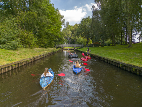 People kayaking and paddling on a peaceful canal surrounded by trees at Hunzepark, Drenthe, Netherlands.