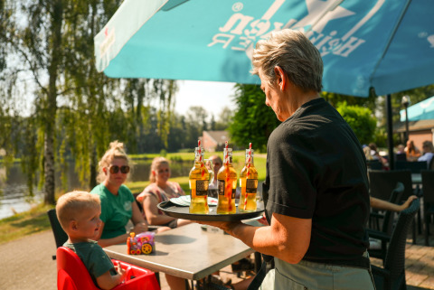 Una camarera sirve bebidas a una familia en la terraza del parque vacacional Hunzepark en Drenthe, Países Bajos.