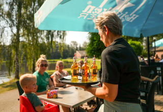 Una camarera sirve bebidas a una familia en la terraza del parque vacacional Hunzepark en Drenthe, Países Bajos.
