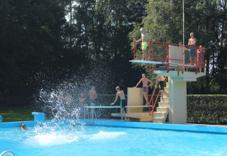 Niños juegan en una piscina exterior con trampolín en Hunzepark, un parque vacacional en Drenthe, Países Bajos.