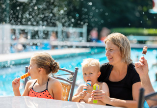 Una familia disfruta de helados junto a la piscina en Hunzepark, un parque vacacional en Drenthe, Países Bajos.