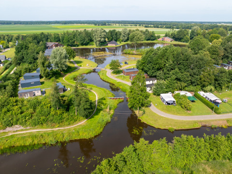 Vista aérea del parque vacacional Hunzepark en Drenthe, Países Bajos, con cabañas, árboles y canales.