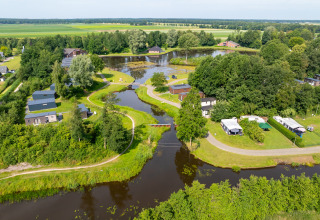 Vista aérea del parque vacacional Hunzepark en Drenthe, Países Bajos, con cabañas, árboles y canales.