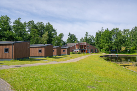 Cabañas y edificio principal junto a un estanque en Hunzepark, parque vacacional en Drenthe, Países Bajos.