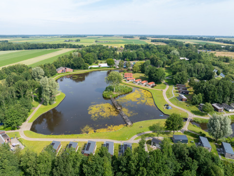 Vista aérea del parque vacacional Hunzepark con lago central, cabañas y áreas verdes en Drenthe, Países Bajos.