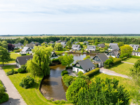 Aerial view of Hunzepark holiday park in Drenthe, Netherlands, with cabins, water features, and greenery.