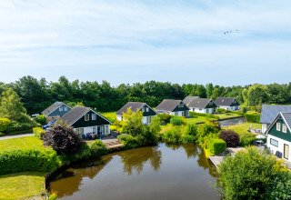 Maisons de vacances près d’un étang à Hunzepark, parc de vacances vert à Drenthe, Pays-Bas.
