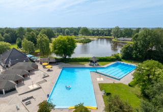 Vista aérea de Hunzepark, un parque vacacional en Drenthe, Países Bajos, con piscina, lago y vegetación.