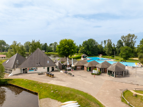 Vue du parc de vacances Hunzepark à Drenthe, Pays-Bas, avec piscine, bâtiments et espaces verts.