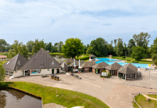 Vista del parque vacacional Hunzepark en Drenthe, Países Bajos, con piscina, edificios y áreas verdes.