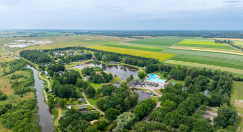 Vista aerea di Hunzepark, villaggio turistico in Drenthe, Paesi Bassi, con laghi, piscina e campi verdi.