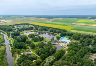 Vista aérea de Hunzepark, parque vacacional en Drenthe, Países Bajos, con lagos, piscina y campos verdes.