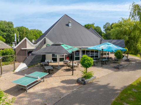 Terrasse extérieure avec tables, chaises et parasols au parc de vacances Hunzepark à Drenthe, Pays-Bas.