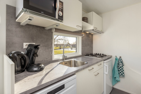 Cocina moderna con fregadero, estufa, microondas y vista exterior, Chalet Comfort 4, Hunzepark, Países Bajos.
