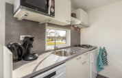 Cocina moderna con fregadero, estufa, microondas y vista exterior, Chalet Comfort 4, Hunzepark, Países Bajos.