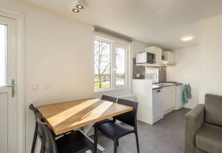 Moderna cucina e sala da pranzo luminosa nel Chalet Comfort 4 a Hunzepark, Paesi Bassi, con vista esterna.