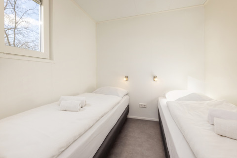 Habitación luminosa en Chalet Comfort 4, Hunzepark, Países Bajos, con dos camas individuales blancas.