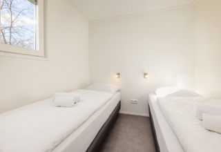 Bright room at Chalet Comfort 4, Hunzepark, Netherlands, with two single beds and minimalist design.