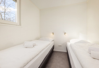 Lyst værelse i Chalet Comfort 4 på Hunzepark, Holland, med to enkeltsenge og hvide vægge.