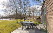 Vista dalla terrazza dello Chalet Comfort 6 a Hunzepark, Paesi Bassi, con tavolo, sedie e lago vicino.
